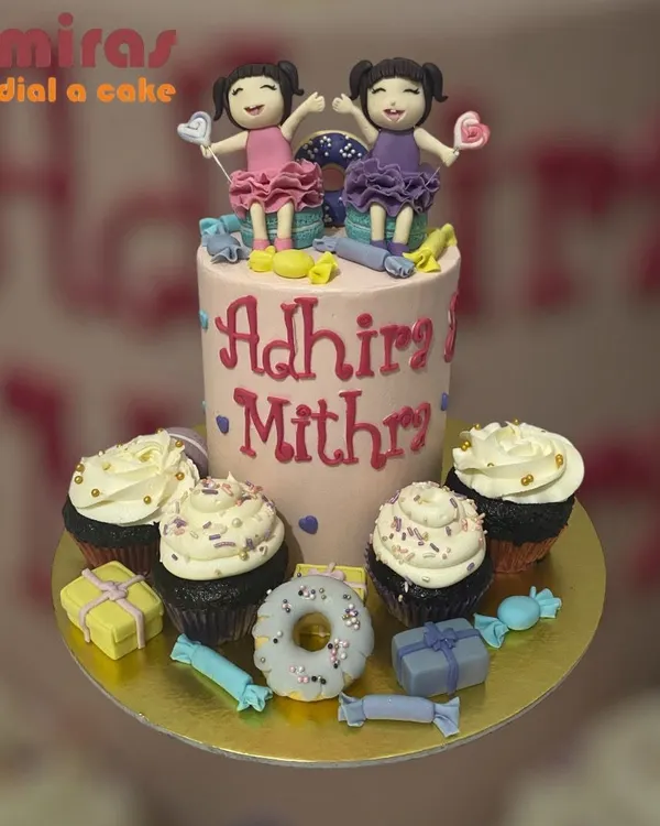 A sweet celebration for twins, this set includes a tall central cake with custom fondant figures of the birthday girls, surrounded by matching cupcakes. The theme is tied together with candy and donut decorations.