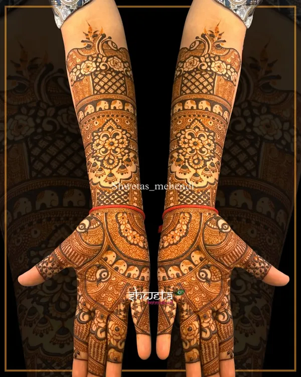 A classic elbow-length mehendi design. The patterns are fully symmetrical, featuring traditional mandala, elephant, and peacock motifs for a rich and elegant look.