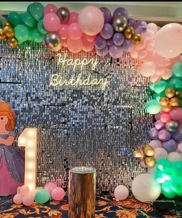 A popular choice for first birthdays, this princess-themed party features a sparkling silver shimmer wall backdrop. It's decorated with a 'Happy Birthday' neon sign, a light-up marquee number '1', and a beautiful pastel and metallic balloon garland.