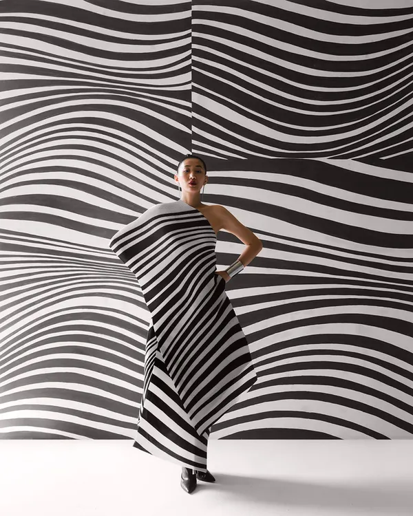 A striking image from a Payal Khandwala campaign, where the model's pleated dress merges with the optical art background. This is an example of creating a total work of art, not just a photograph.