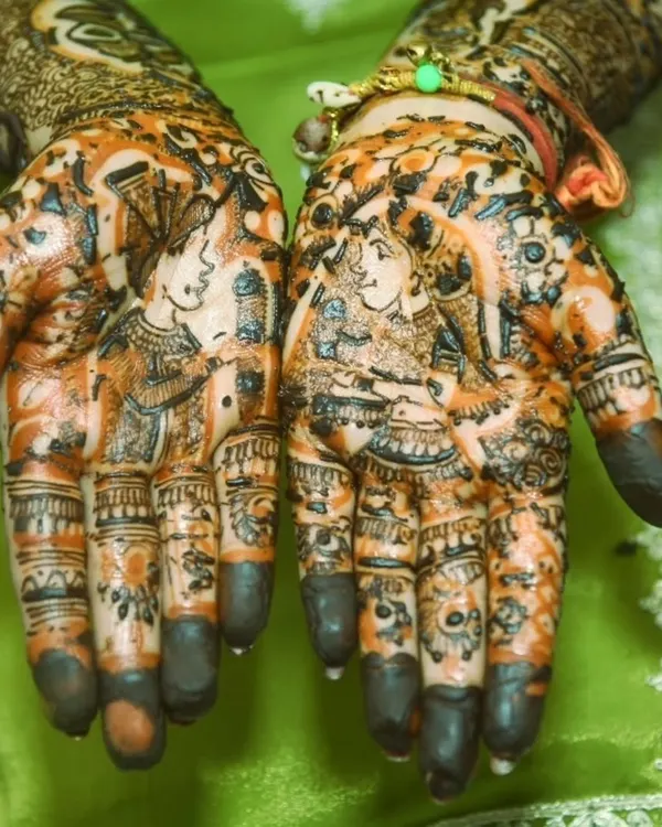 The beauty of bridal mehendi is in the details. This close-up shows the rich color and intricate patterns, featuring portraits of the bride and groom.