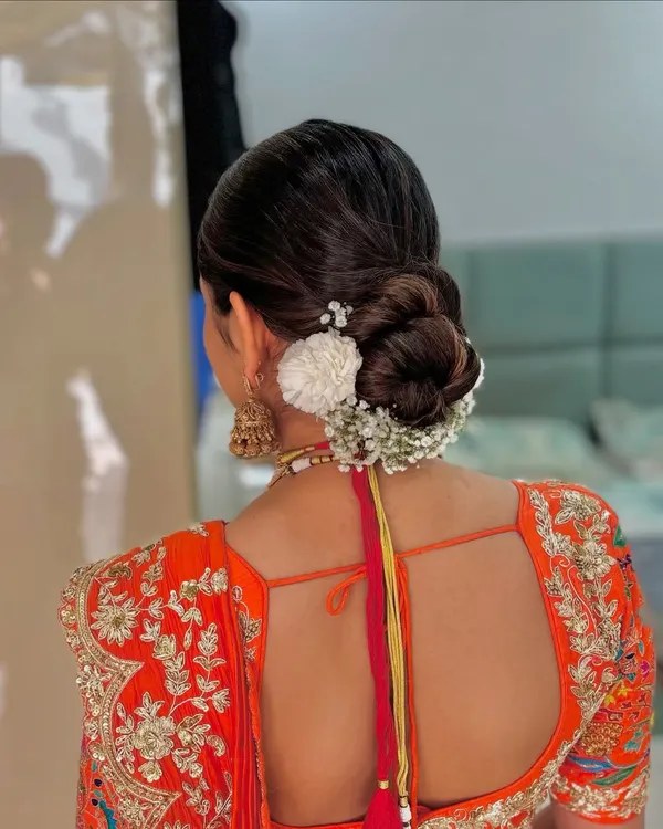 A classic bridal bun adorned with a combination of white flowers and baby's breath. This is a timeless and elegant choice for any bride.