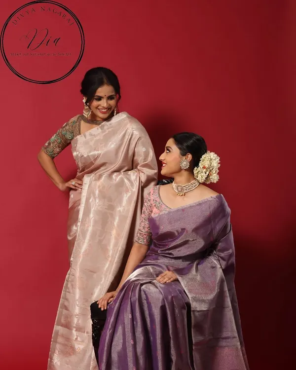 A beautiful shot from a campaign, showcasing elegant makeup on two models in traditional tissue silk sarees. The looks are soft, complementary, and highlight a timeless South Indian aesthetic.