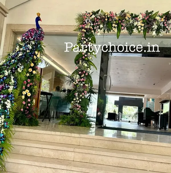 This grand entrance features a floral peacock sculpture with a long, cascading tail made of flowers, wrapping around the doorway. It's a spectacular welcome piece that immediately wows guests.