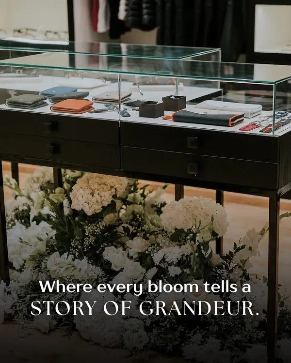 **(Hero Item)** This is where product meets poetry. For the Maybach merchandise launch, we designed this bespoke floral installation to cradle the display case, turning a simple product showcase into a statement of grandeur and luxury. The lush white hydrangeas and roses create a soft, opulent bed, making the sleek leather goods feel like treasured jewels.