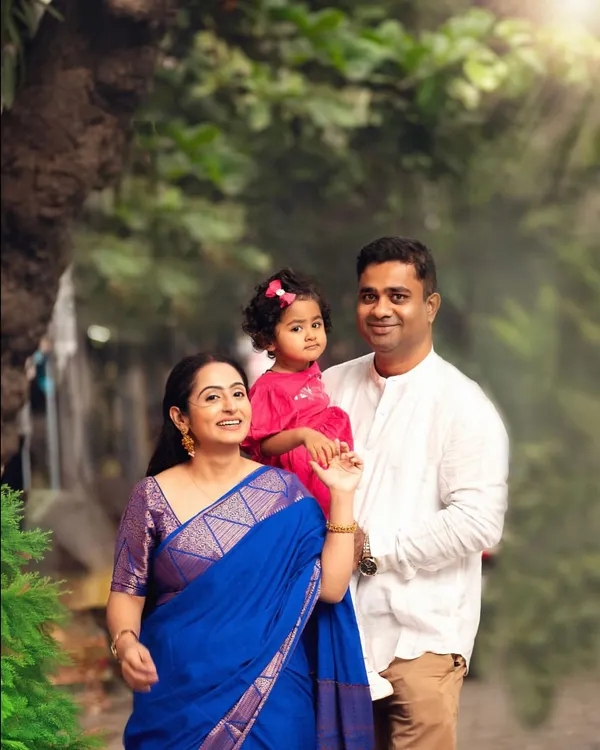 A beautiful family portrait taken outdoors with a touch of sunlight. The traditional outfits and natural setting create a perfect blend of culture and candid love.