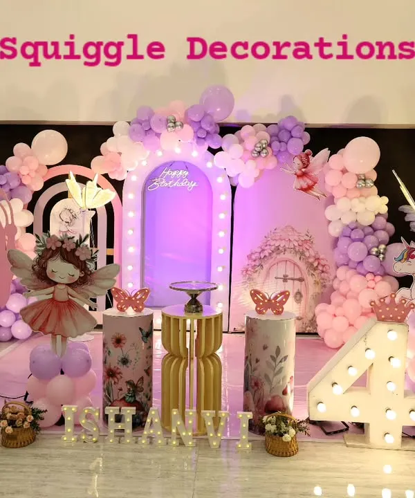 A truly enchanting butterfly-themed 4th birthday party. The setup includes large pink butterfly wings, a fairy cutout, a unicorn, and a beautiful purple and pink balloon arrangement.