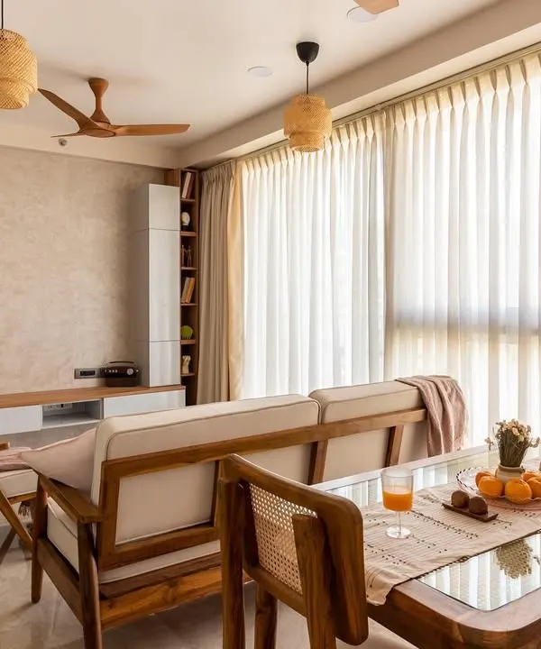A complete view of the Japandi-style living and dining area, where teak wood furniture, rattan pendants, and sheer curtains come together to create a harmonious and light-filled environment.