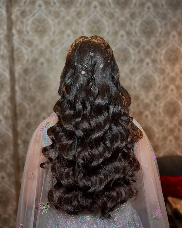 A cascade of voluminous curls. This open hairstyle is perfect for a glamorous sangeet or reception look, adding movement and drama.