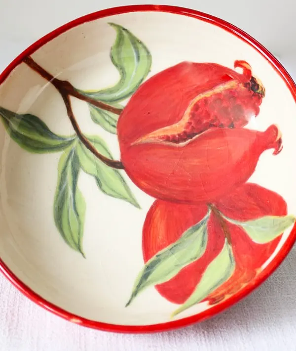 Another view of the Pomegranate Bowl, showing the depth of the red and green hand-painted details. It's a versatile piece, perfect for serving salads, pasta, or simply as a decorative centerpiece.