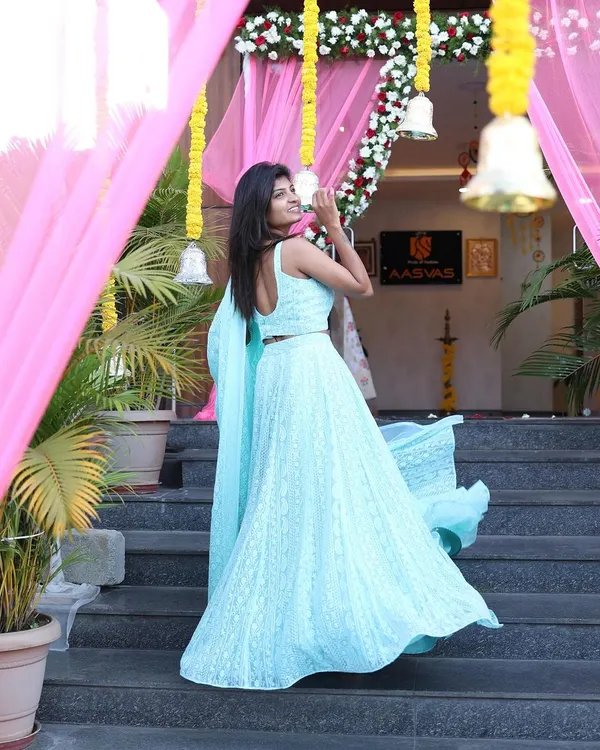 An apparel shoot for a designer studio, featuring a beautiful light blue lehenga. The movement in the skirt and the elegant backdrop of the entrance create a welcoming and aspirational fashion photograph.