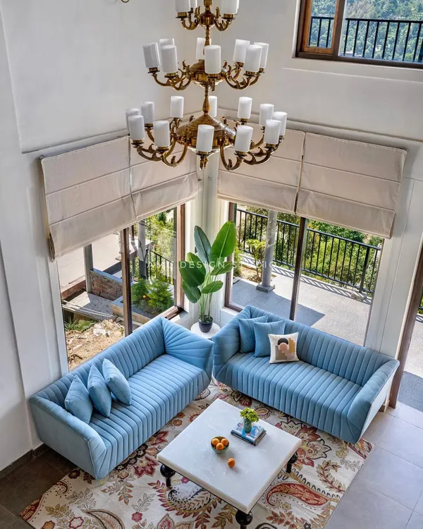 Our hero piece: A breathtaking living room in a mountain home where our custom-designed sky-blue velvet sofas create a serene oasis. The double-height windows frame the majestic view, while the furniture provides a luxurious space for relaxation and connection.