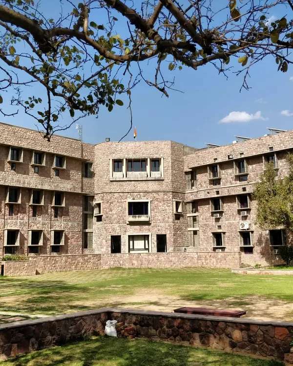 The main academic block at IIHMR, built with a pinkish-grey quartzite sourced from a nearby village. The design uses traditional elements like precast *jaalis* and *chajjas* to create a building that is modern yet deeply connected to local craft.
