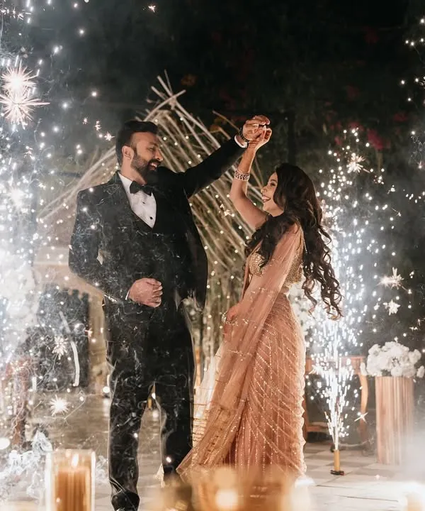 A magical Sangeet night moment, with the couple dancing under a shower of sparklers. The rustic, teepee-style backdrop and warm lighting create an enchanting and celebratory atmosphere.