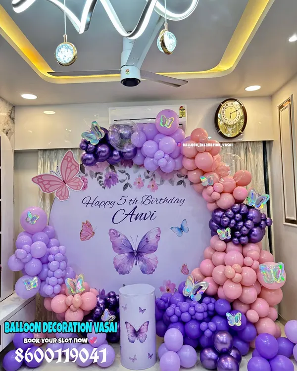 Anvi's 5th birthday with a beautiful butterfly theme. This setup features a round backdrop with a personalized message, surrounded by a stunning arch of purple and pink balloons.