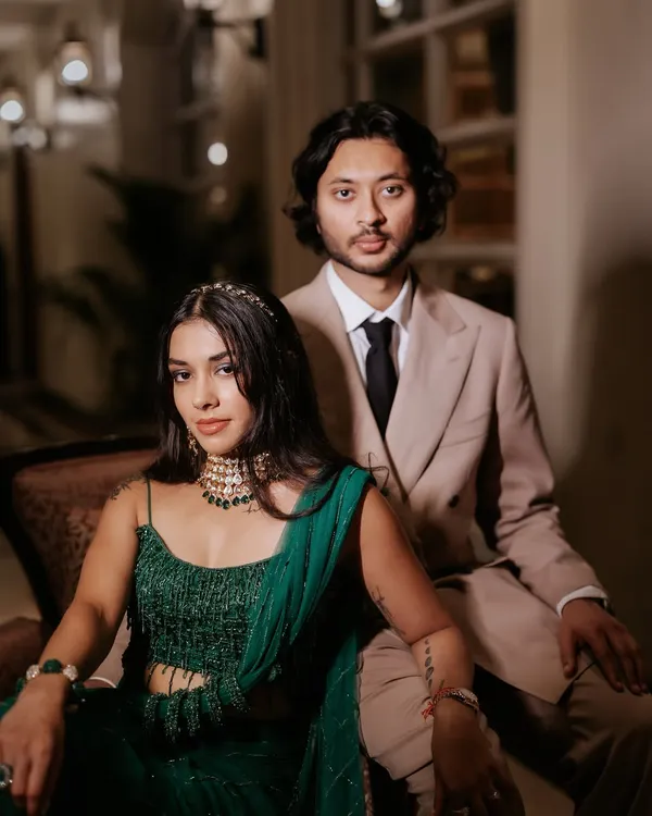 A modern and chic couple portrait. The bride's evening look is glamorous and edgy, with defined eyes and glowing skin that contrasts beautifully with the dark, moody lighting.