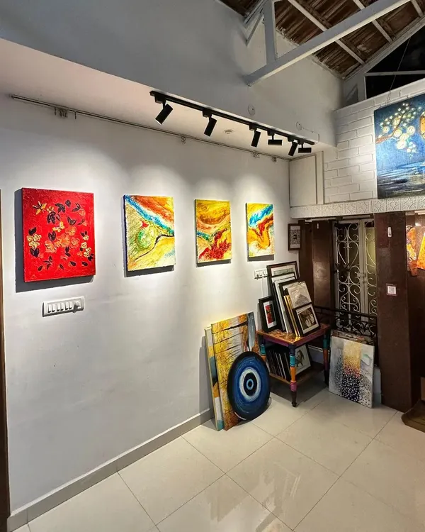 A view of our gallery's main wall, showcasing a variety of artworks under professional track lighting, with stacks of more canvases ready for collectors to explore.