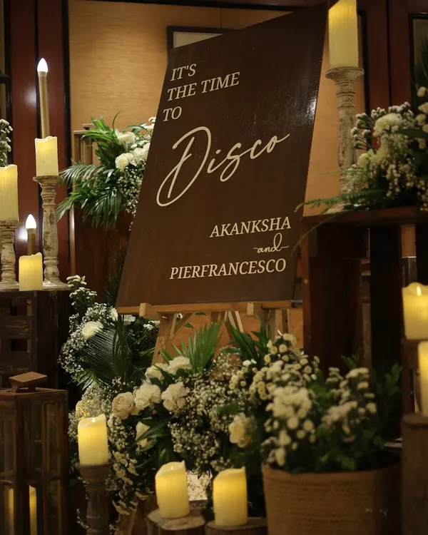 The entrance to a "Milan to Mumbai" themed cocktail night. The elegant brown and white color scheme, candlelight, and floral arrangements set a sophisticated and romantic tone for the party.