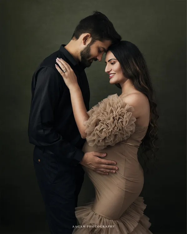 A truly elegant fine art maternity portrait. The couple's pose and the soft lighting against the dark backdrop create a feeling of timeless romance and anticipation.