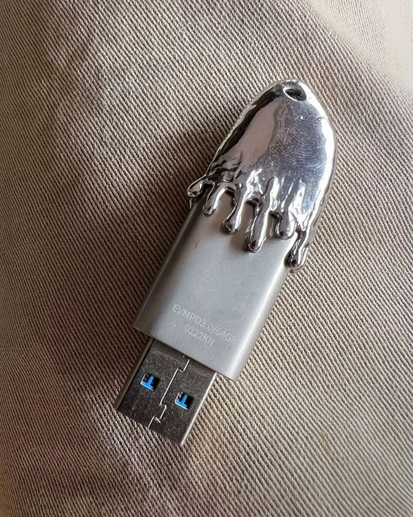 A custom-designed USB drive I made for my DJ sets. The top is a solid piece of silver with a melting, 'frostbite' effect. It’s a functional item that also serves as a piece of branding and personal style.