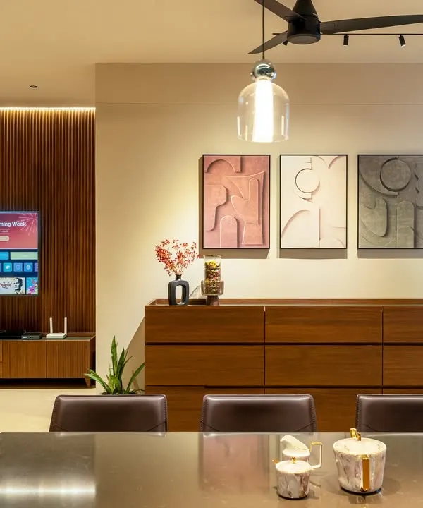 The dining and living area of the Humaize Apartment, where a wood-paneled feature wall houses the TV. A custom sideboard and contemporary art create a sophisticated yet functional space for the family.