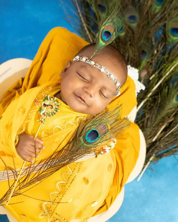 A portrait of a smiling newborn as little Krishna, complete with a jeweled headband and peacock feathers. This is one of my most requested cultural themes, captured in my Navi Mumbai studio.