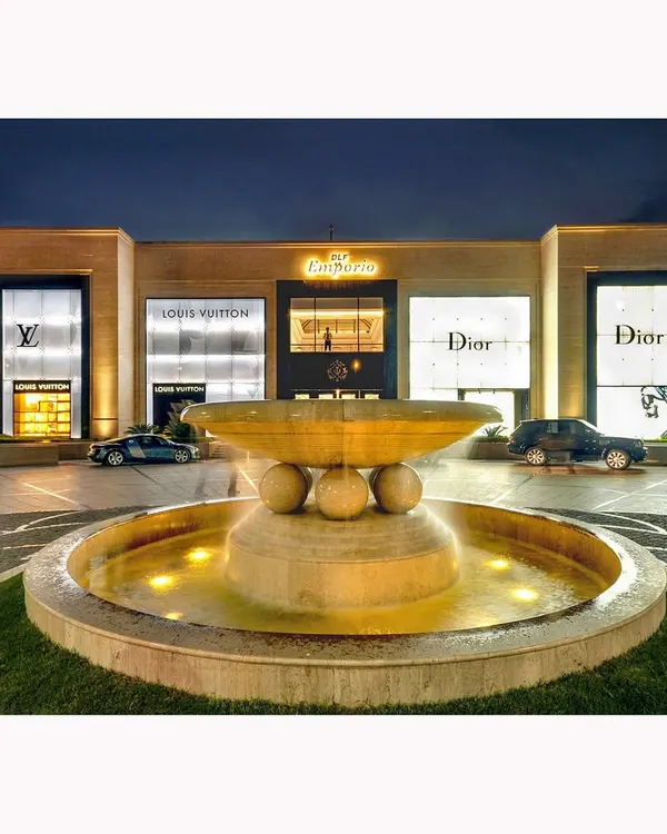 The facade of the DLF Emporio mall at dusk. The glowing storefronts of luxury brands like Louis Vuitton and Dior create a powerful statement of premium commercial real estate.