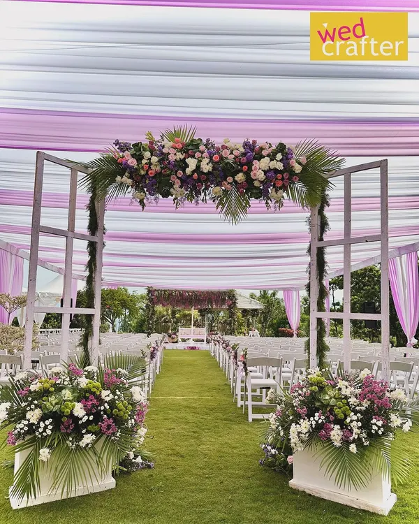 A dreamy garden wedding aisle. We used a white and lilac draped canopy, a floral archway, and lush arrangements to create a breathtaking path for the bride to walk down.