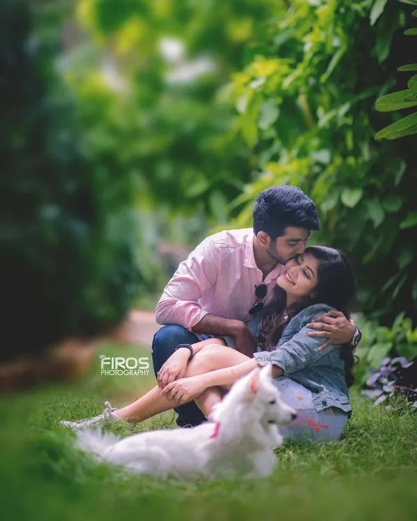 A perfect, tender moment during a pet-friendly couple shoot. The man kisses his partner's forehead while their fluffy white dog relaxes in the foreground, completing this beautiful family picture.