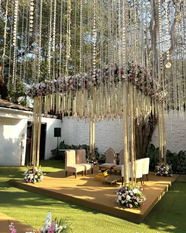 A closer look at a custom mandap designed to feel ethereal and light. The structure is adorned with a mix of pink and white florals, with delicate strings of flowers and crystals that catch the sunlight beautifully.