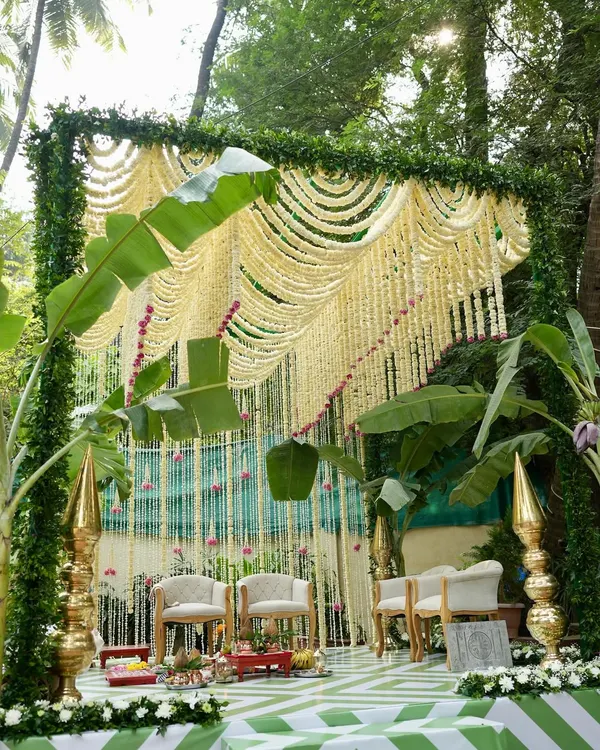 A dreamy, minimal mandap design perfect for an intimate garden wedding. We created a breathtaking curtain of tuberose garlands framed by lush greenery and banana leaves, with elegant seating for the couple.