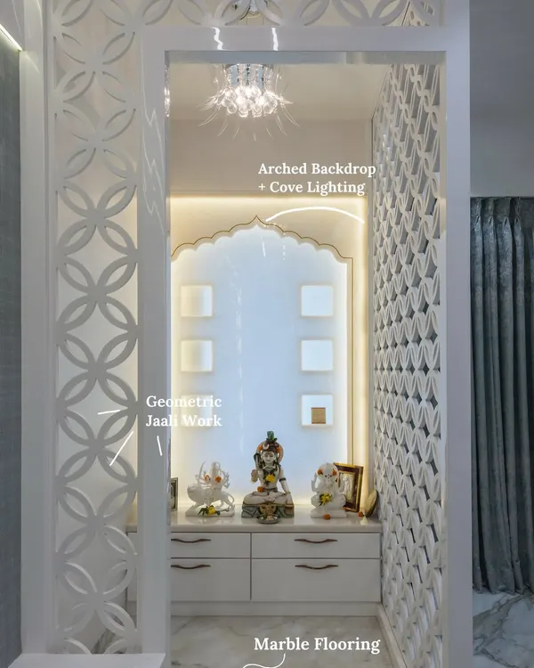 A serene white mandir featuring circular jaali panels, an arched backdrop with warm cove lighting, and luxurious marble flooring. This design transforms a prayer space into the heart of the home.