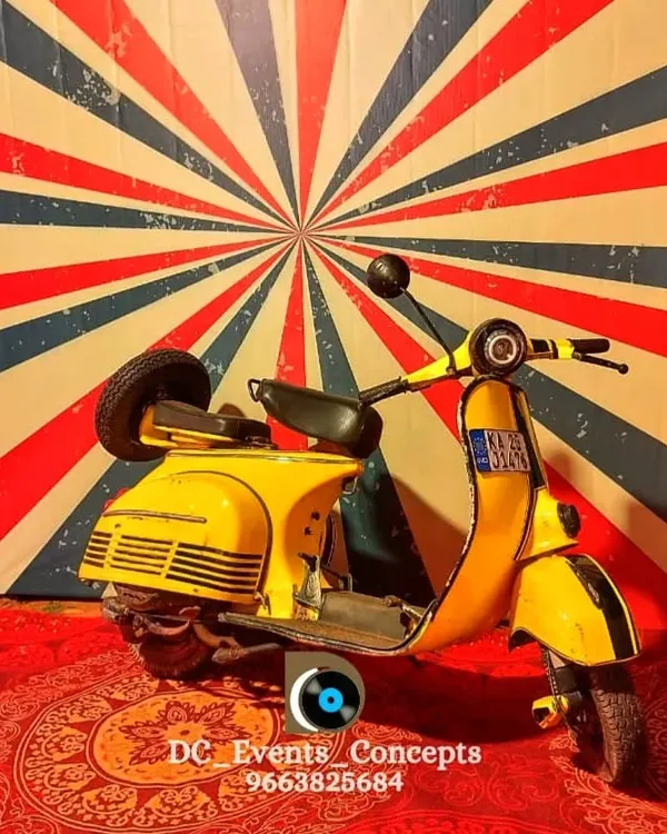 A fun and quirky retro-themed photo booth featuring a vintage yellow scooter against a vibrant sunburst backdrop. This is a great way to add an interactive and memorable element to any party.