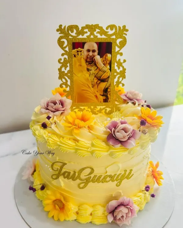 Celebrating the divine presence with sweetness and devotion. A beautiful yellow floral cake with a "Jai Guruji" blessing.