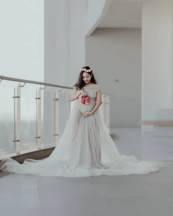 A classic and beautiful maternity portrait. The flowing gown and the simple act of holding tiny shoes create a powerful image of anticipation and love.
