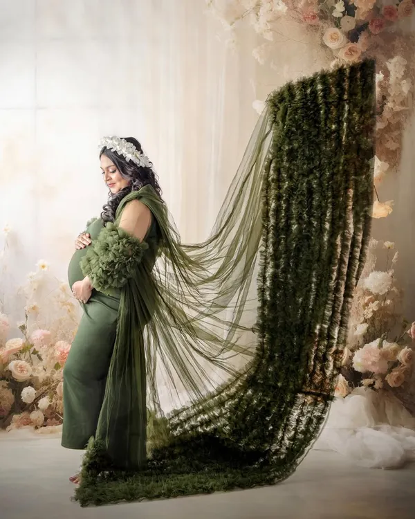 A dramatic portrait featuring a stunning green gown with a long, textured train. The pose is designed to show off the incredible detail of the dress and create a powerful, statuesque look.