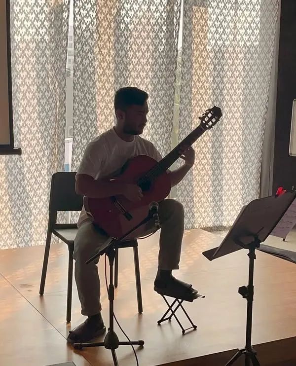 A student deep in concentration during his ABRSM classical guitar practical exam. We focus on comprehensive grade exam preparation, ensuring every student is poised and ready for their assessment.