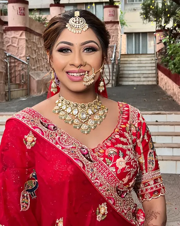 A beautiful, smiling bride ready for her big day. I created a classic bridal look with a defined eye, radiant skin, and a bright smile to match her stunning red lehenga.
