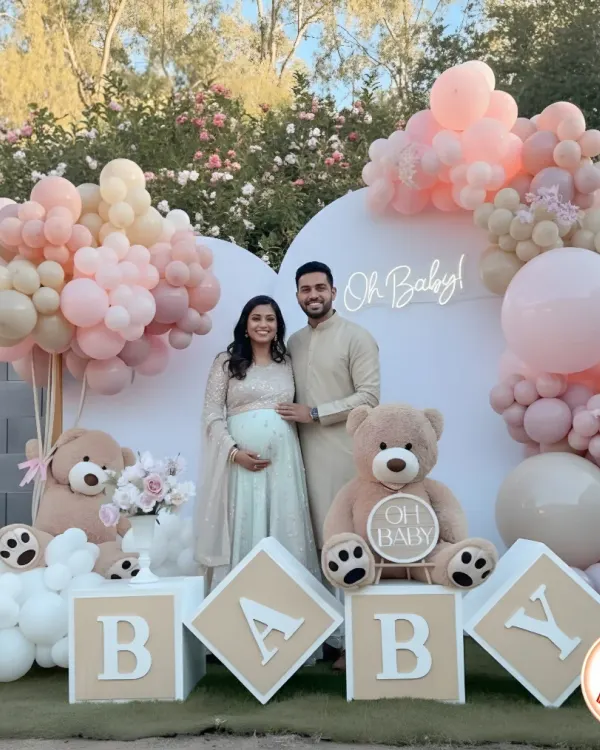 A beautiful couple at their 'Oh Baby' teddy bear themed baby shower. The outdoor setting with soft pink and neutral balloons created a warm and loving atmosphere.