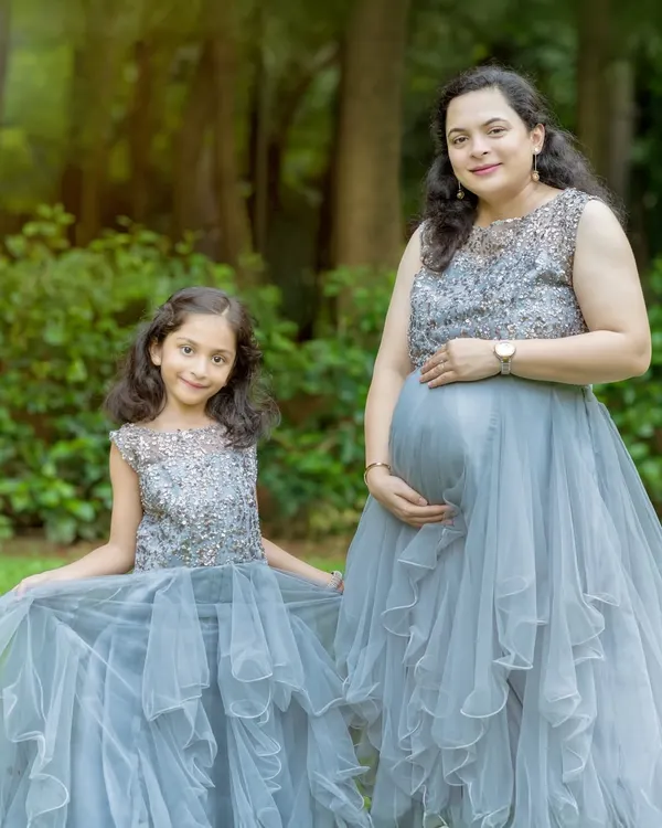 A perfect match. Our grey embellished gowns for mom and daughter feature sparkling bodices and layered tulle skirts, creating an elegant and cohesive look for a family maternity shoot.