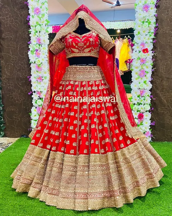 This is the quintessential bridal lehenga, designed for the bride who wants a classic and royal wedding day look. The rich red fabric is covered in intricate gold embroidery, creating a heavy, luxurious feel, complete with a double dupatta for a truly grand entrance.