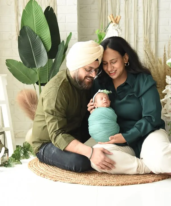 A happy family portrait with parents and their newborn, set against a bright and airy boho-themed backdrop. These full-family shots are perfect for celebrating your new arrival together.