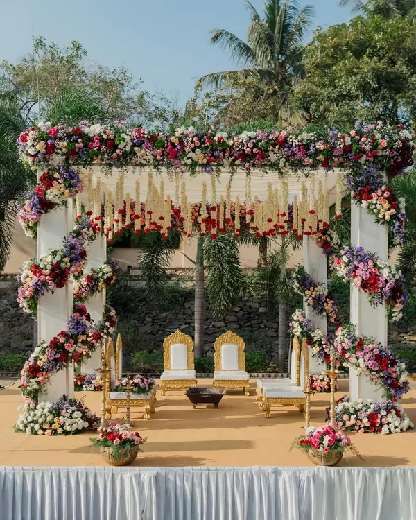 A breathtaking floral mandap, overflowing with colorful blooms and traditional hanging elements. This design creates a vibrant and sacred space for a Hindu wedding ceremony.