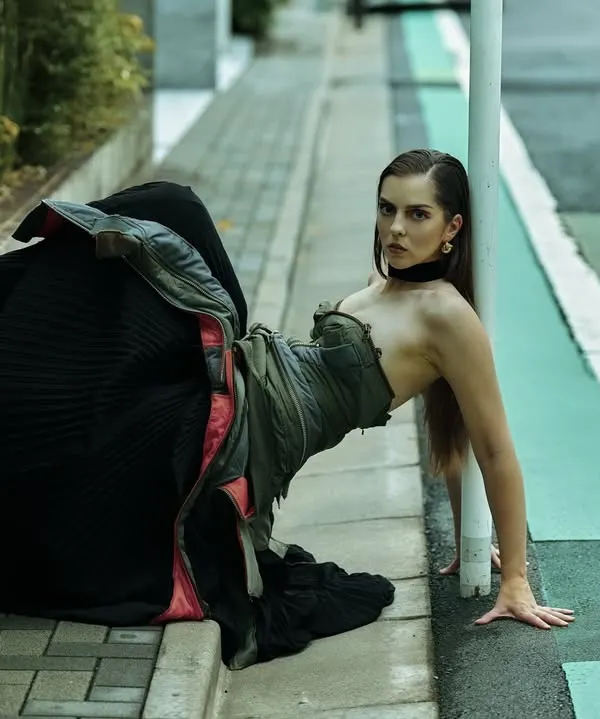 An unconventional pose on a Tokyo sidewalk. I’m always studying how lines cut through a scene. Here, the green bike lane and the curb create a graphic backdrop for the model's architectural pose and voluminous dress.
