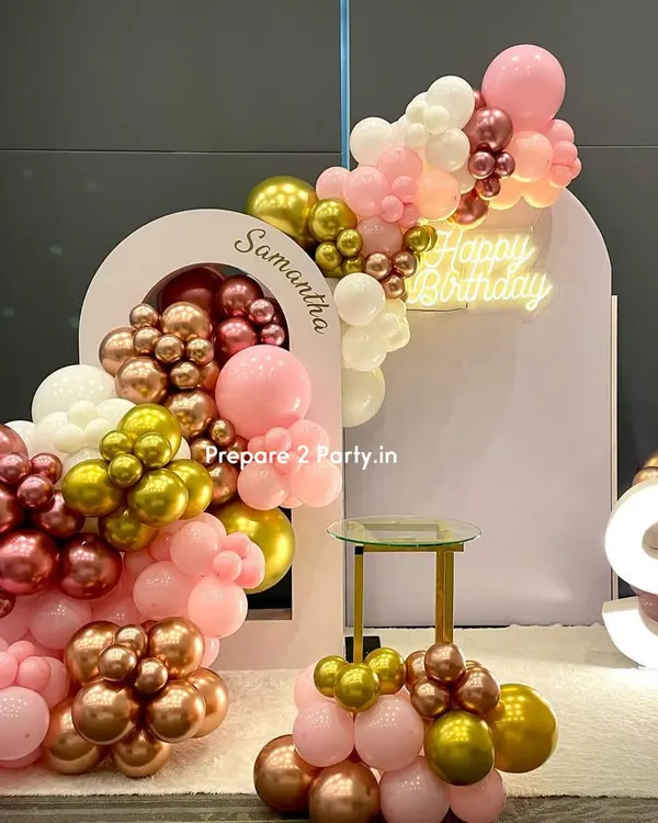 This premium birthday backdrop was personalized with the name 'Samantha' on a custom arched panel. The design features a cascading balloon garland in pink, rose gold, and white, a 'Happy Birthday' neon sign, and a light-up marquee initial.