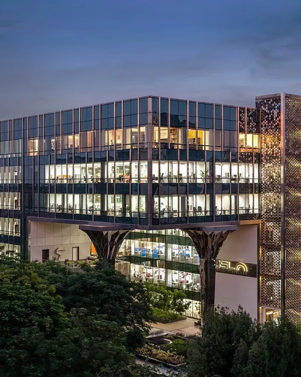 A wide-angle evening shot of the Jindal Stainless Steel Office, showcasing the building's impressive scale, illuminated interiors, and the unique faceted steel-clad columns we designed for the entrance.