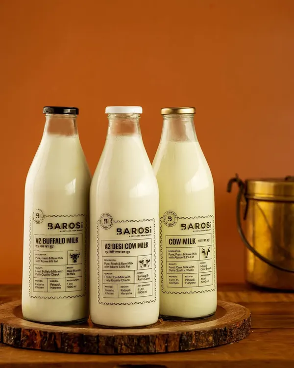 A clean product shot of Barosi's range of A2 milk. The warm, simple background and rustic wooden tray highlight the farm-fresh quality of the products, perfect for a website's product page.