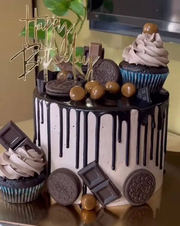 A decadent chocolate overload cake, topped with Oreos, chocolate bars, and cupcakes.