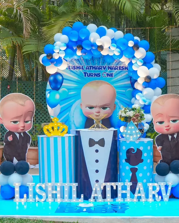 Lishil Atharv's first birthday was all business with this fun Boss Baby theme. The outdoor setup features a central Boss Baby character, a blue and white balloon arch, and tuxedo-themed plinths for a party that's the "boss."