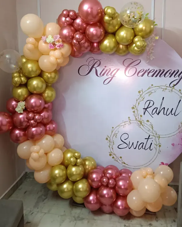 Make your ring ceremony extra special with a personalized backdrop. This circular board is custom-printed with the couple's names and event title, framed by an elegant balloon arrangement in gold, peach, and rose gold tones.